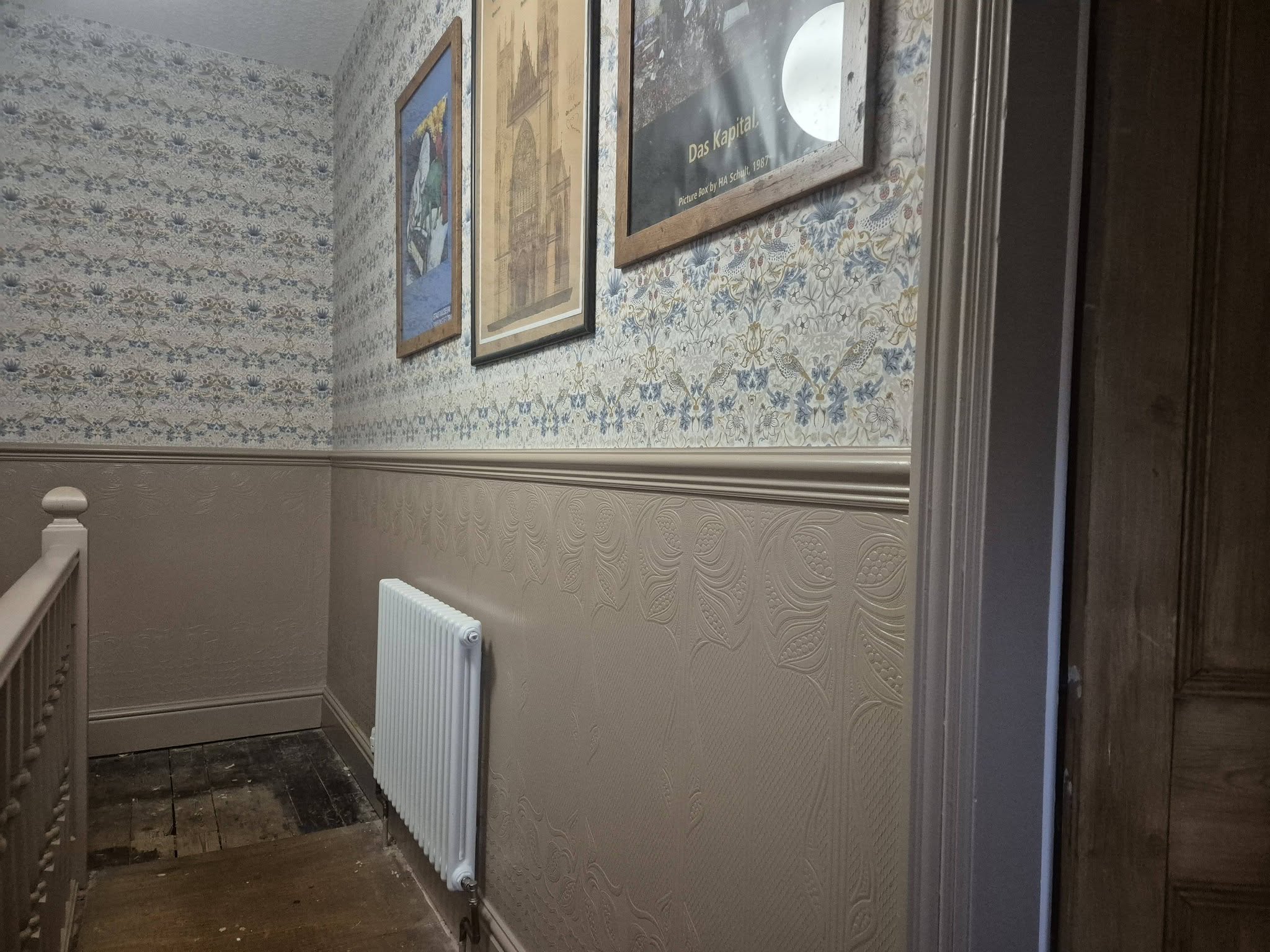 Corner of a decorated landing with pictures hung above the dado rail