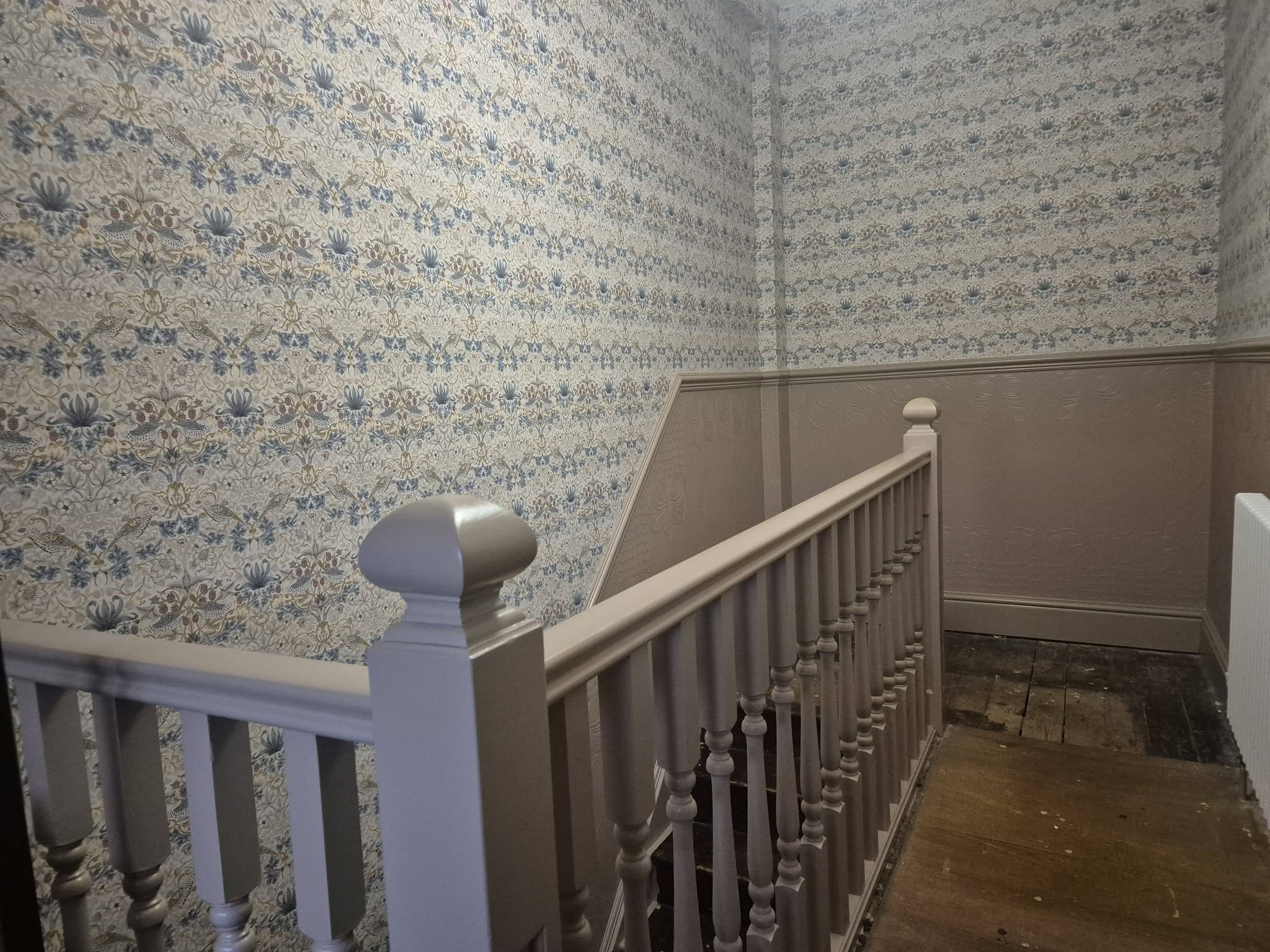 Painted banister and spindles on a newly wallpapered landing